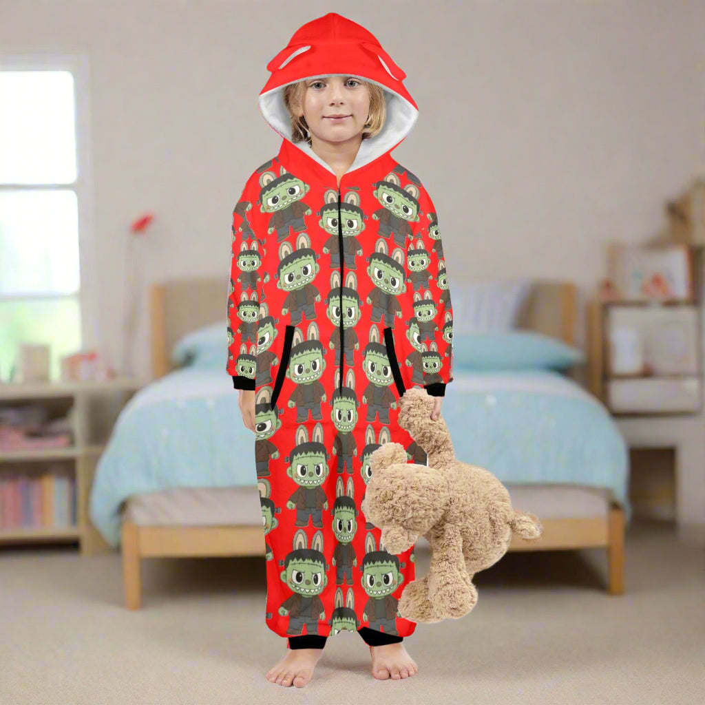 Child wearing a red onesie with green animal pattern, holding a teddy bear on a white background